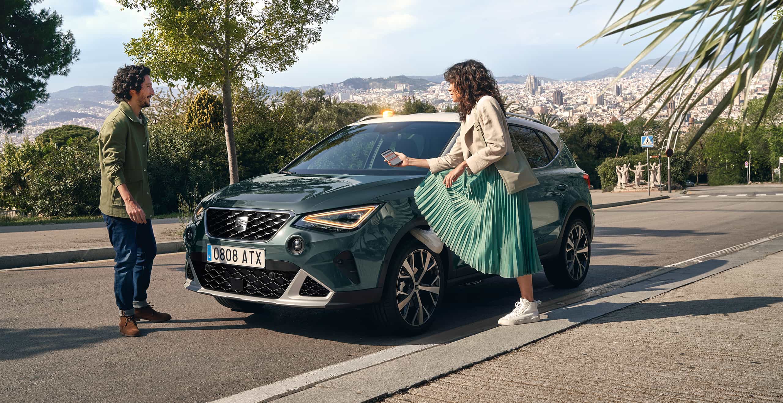 Woman with her foot on SEAT Arona´s wheel looking at her smartphone