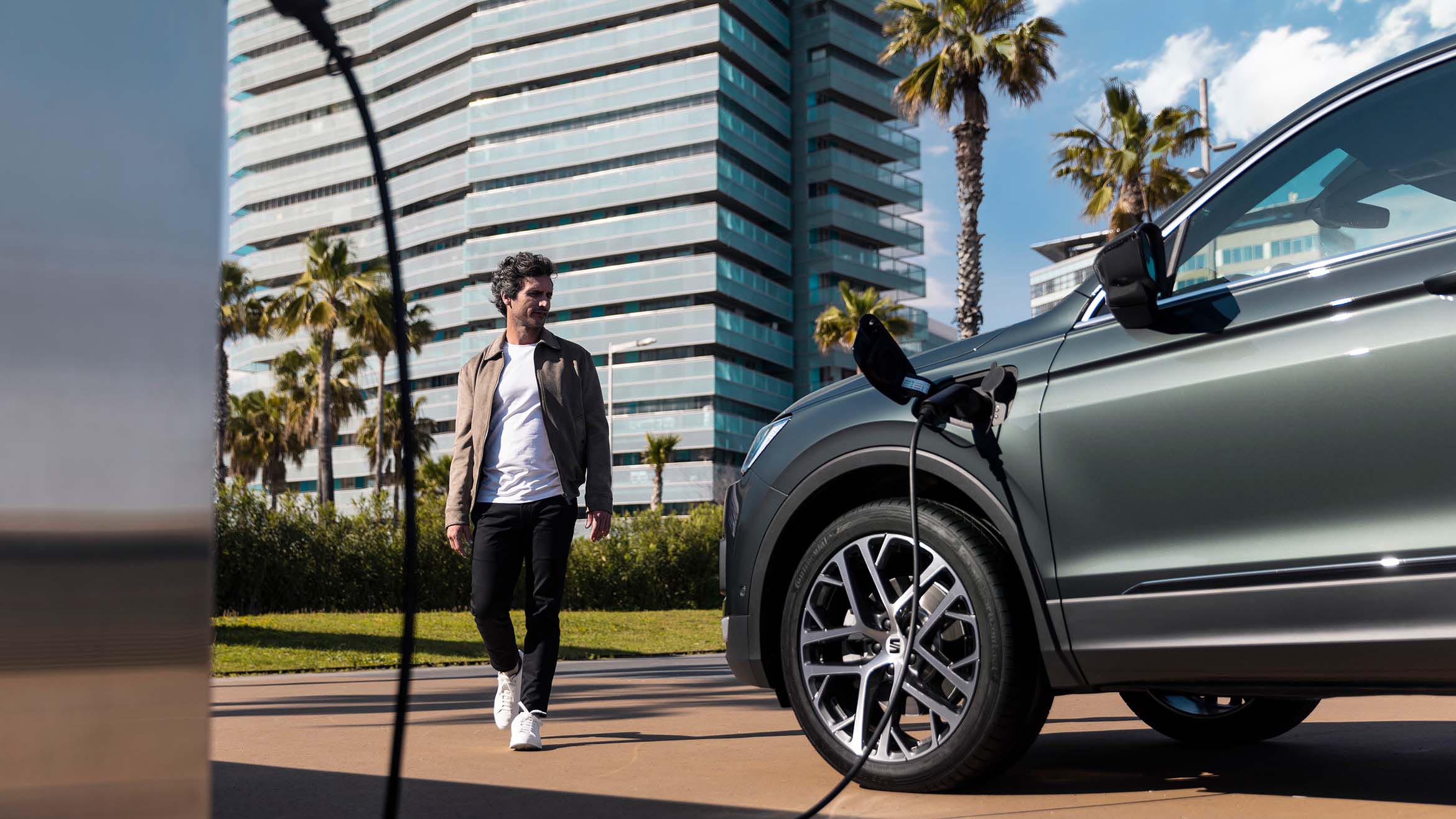 A person walking to the new SEAT Tarraco XPERIENCE Dark Camouflage colour while charging