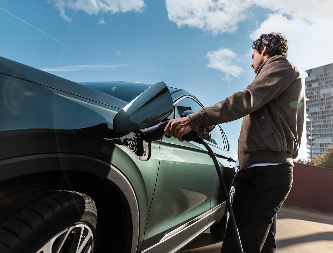 Man charging a new SEAT Tarraco XPERIENCE e-HYBRID Dark Camouflage colour   
