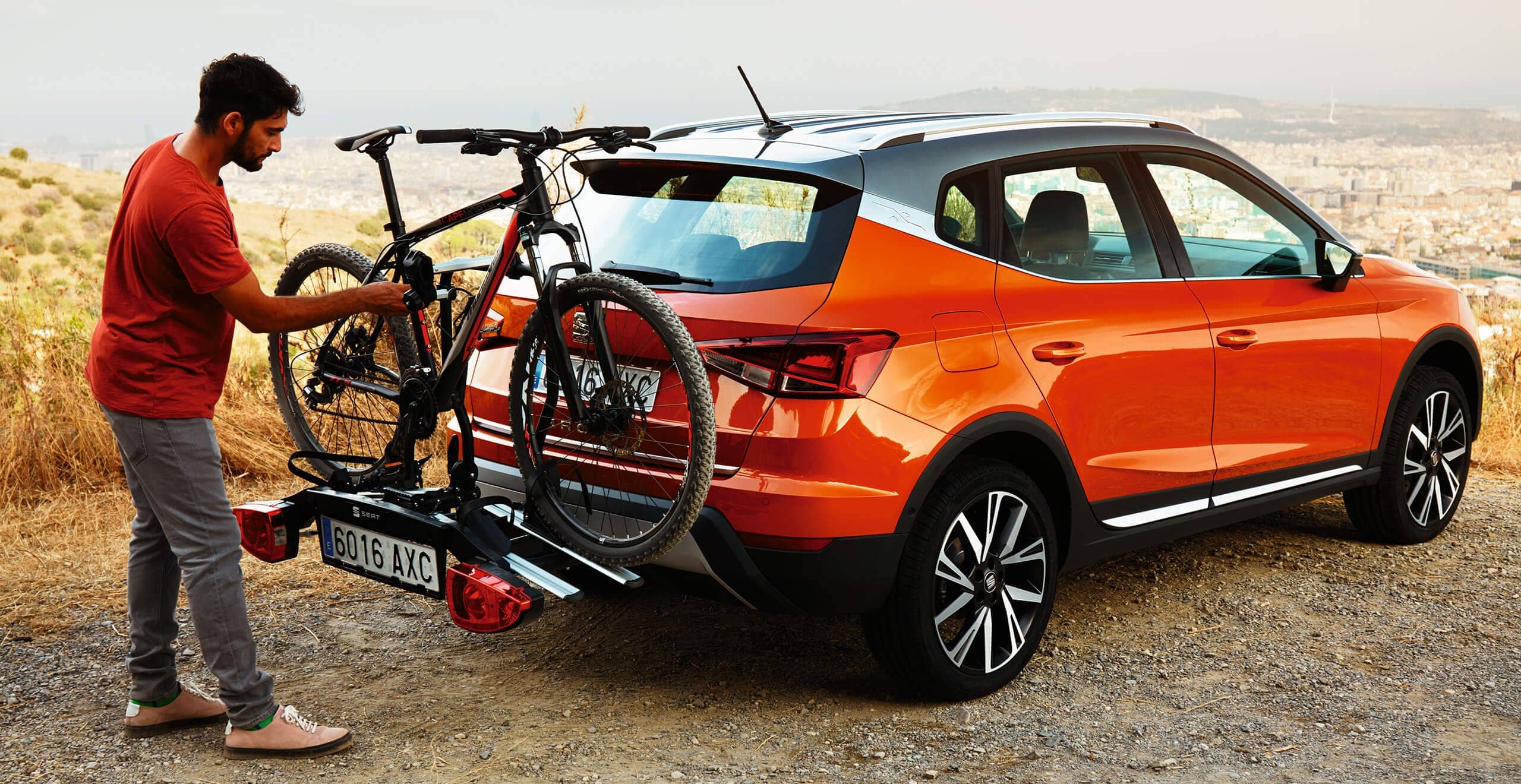 SEAT new car services and maintenance – man placing a bicycle on the bike rack at the back of a SEAT Arona crossover